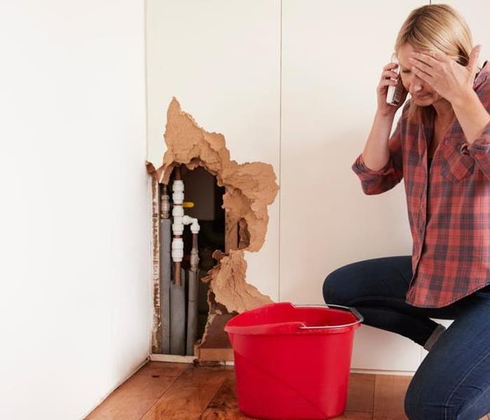 A woman calls for help as she discovers a burst pipe inside her wall.